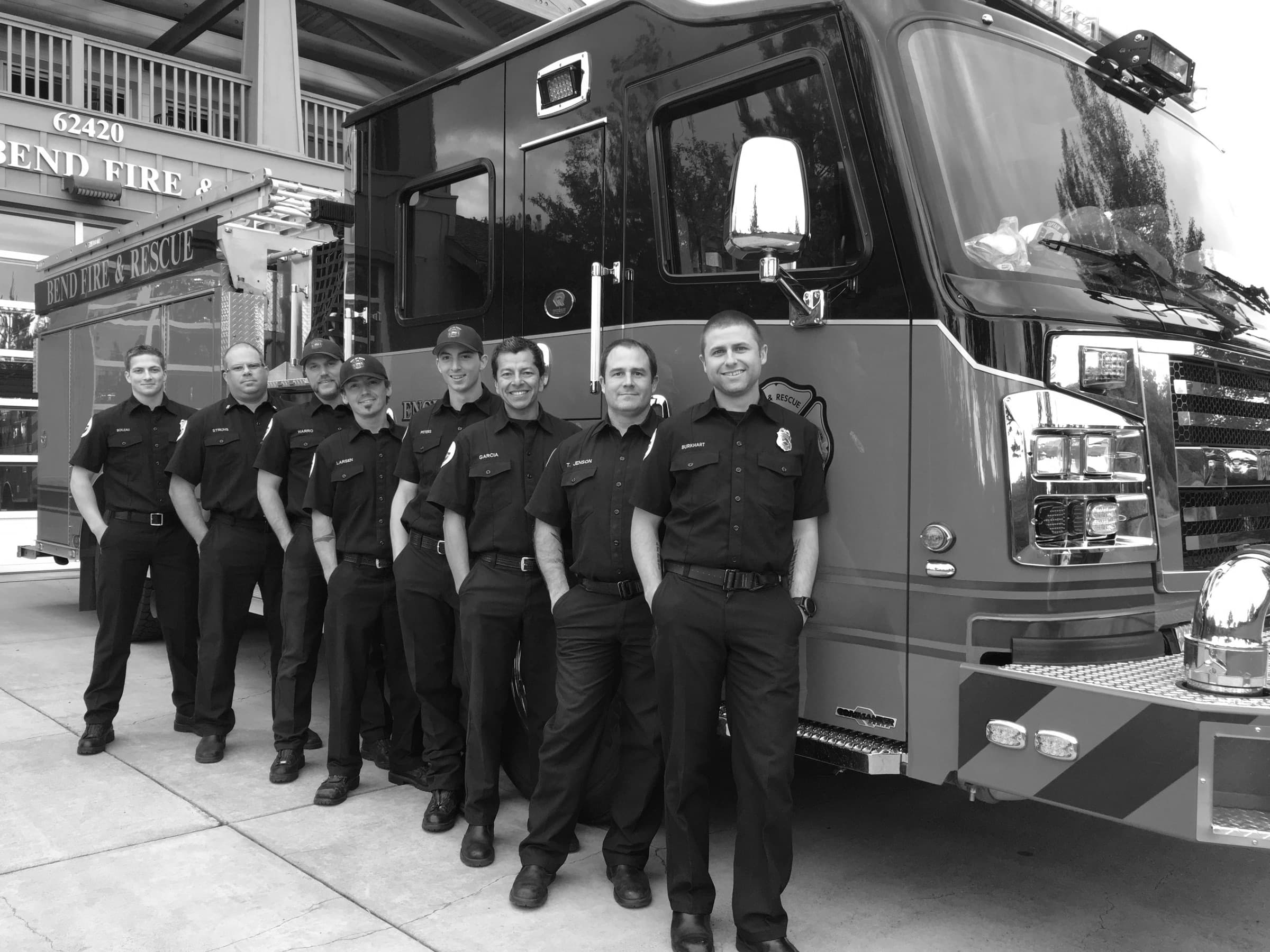 Bend firefighters standing in a line beside a fire engine outside the station